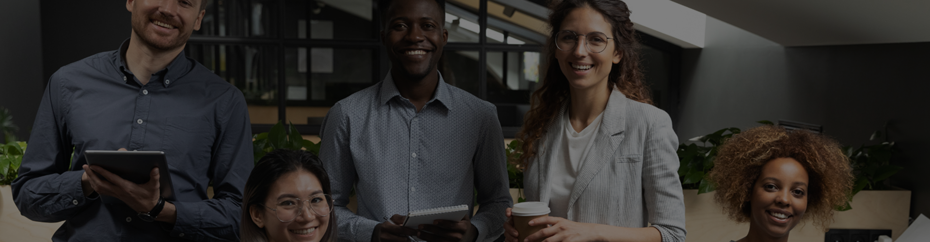 Group of professionals in an office, smiling at the camera banner
