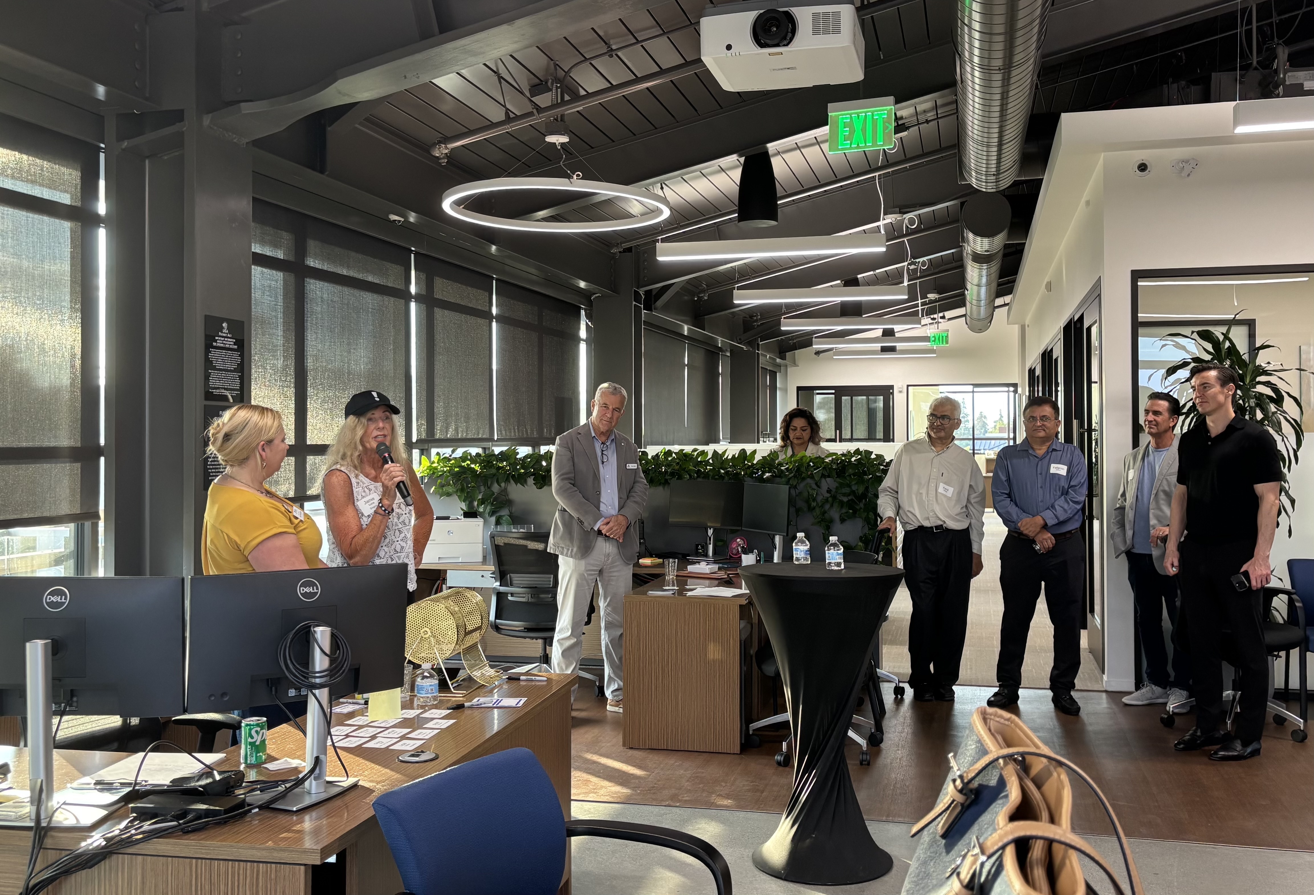 A small group of professionals gathers inside a modern, open-plan office.